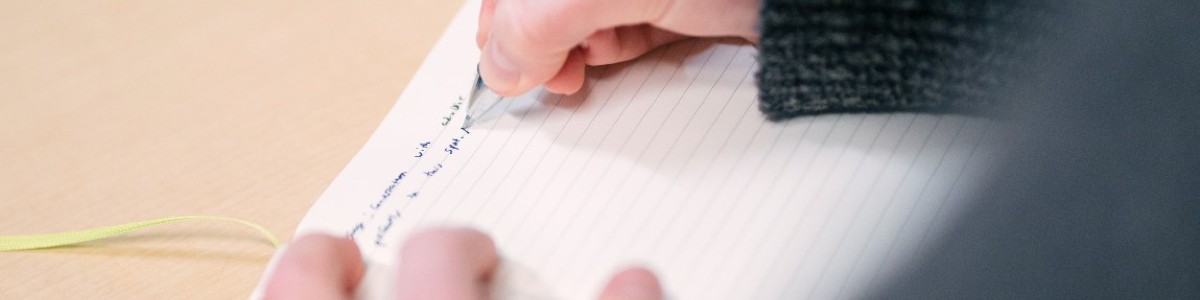 hand holding pen and writing in notebook
