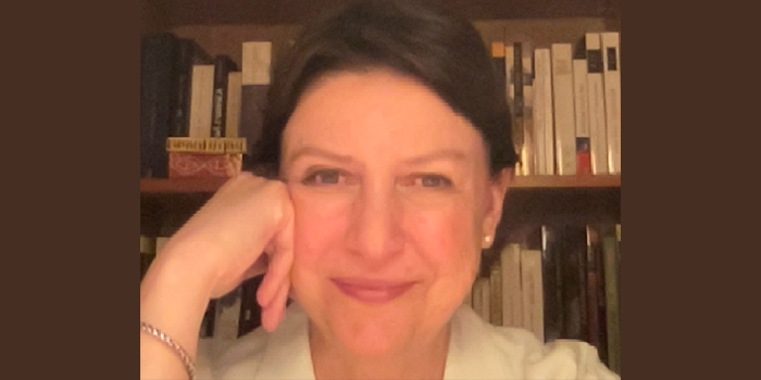 Catalina with her hand on her cheek, in a book lined office