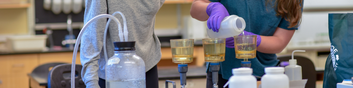 Students pouring liquids into lab equipment