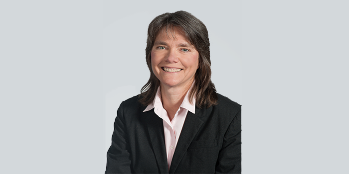 Betsy Hoza in portrait against a gray background