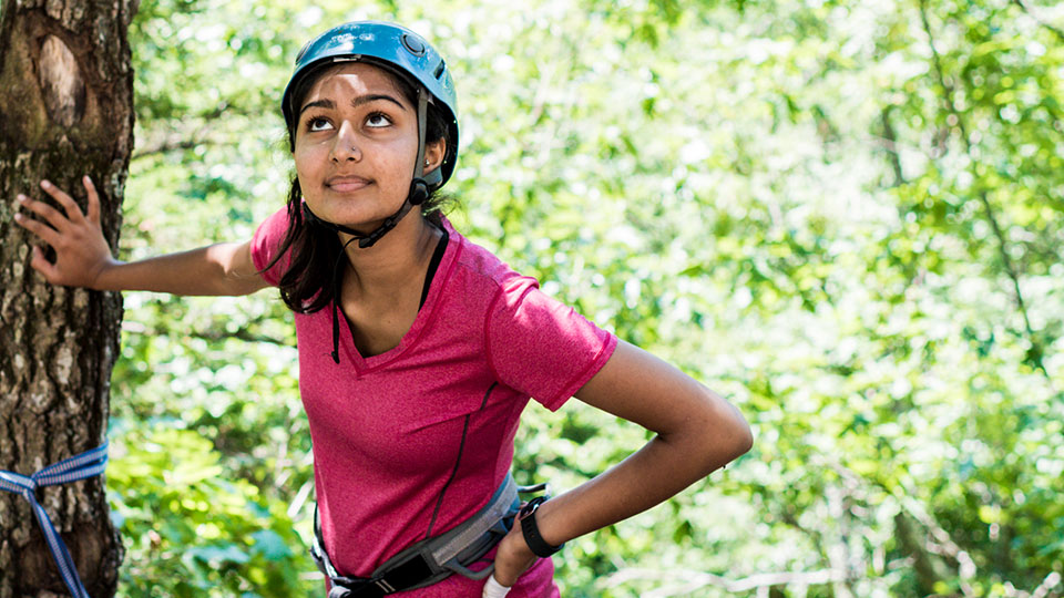 student leaning against a tree looking up