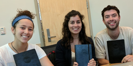 three students holding binders smiling