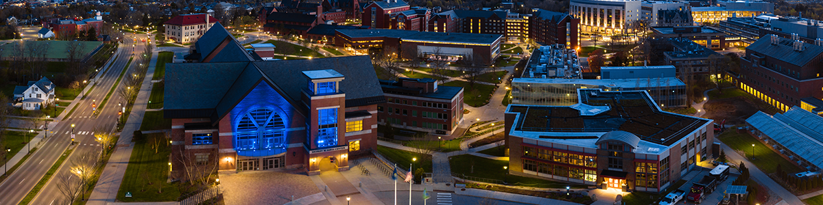 Davis Center lit up with blue lights for healthcare workers with adjacent buildings at sunrise