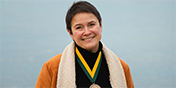 Cristina with medal around her neck smiling with lake champlain in the background