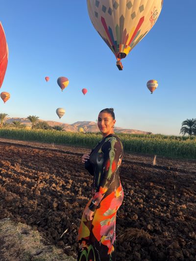 Isabel outdoors with floating air balloons filling the sky in the background