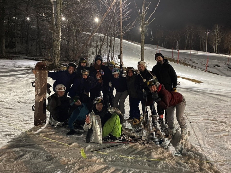 Group of students posing for group photo next to a ski slope at night