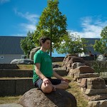 Man meditating while sitting on a large rock