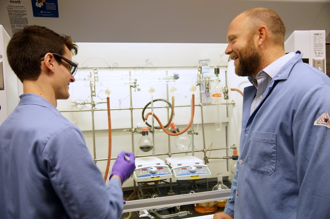 faculty and student discussing experiment with formulas and equipment