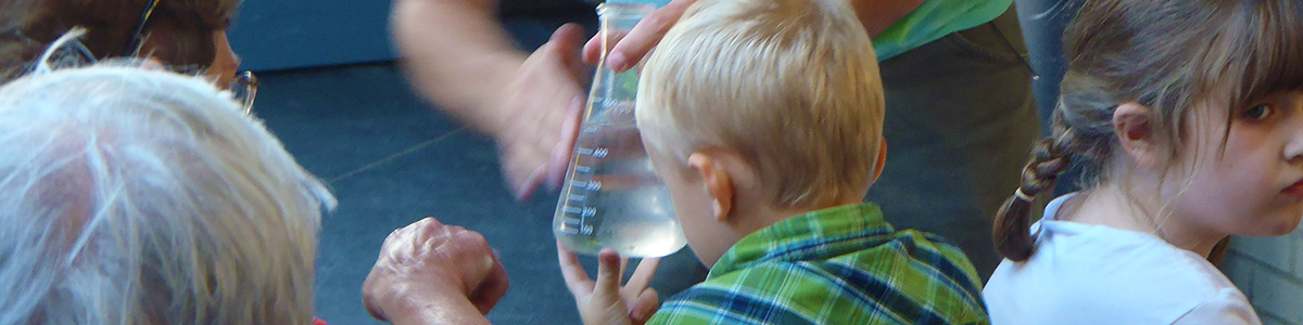 Young boy and adult look at flask