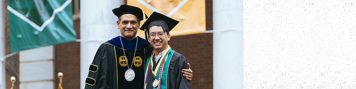Jonah Stern, wears medal, and stands on stage with UVM President Garimella at 2023 Commencement Ceremony.