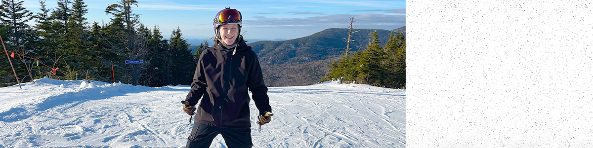 Katie Conlon stands on snowboard atop resort ski trail.