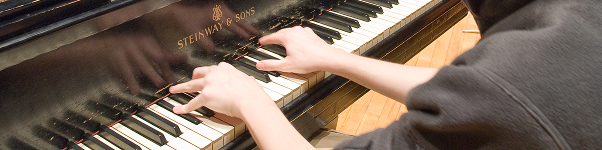 Close up of a student playing a Steinway grand piano.
