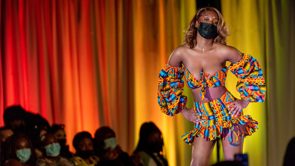 Student wears colorful designs on the runway at the annual fashion show.