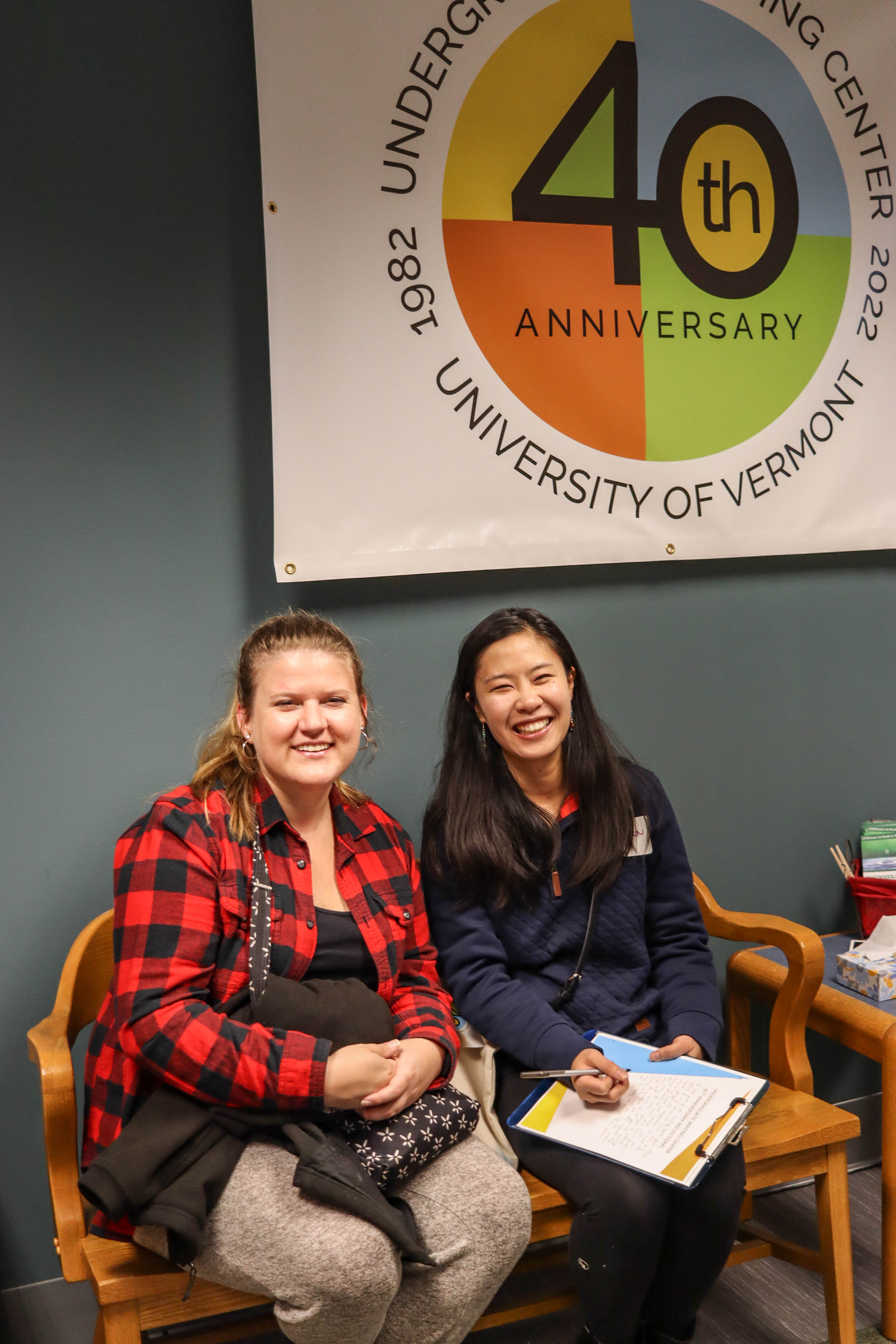 Alumni tutor Samantha DuBrown and her guest sat on the reception bench beneath the 40th anniversary sign.