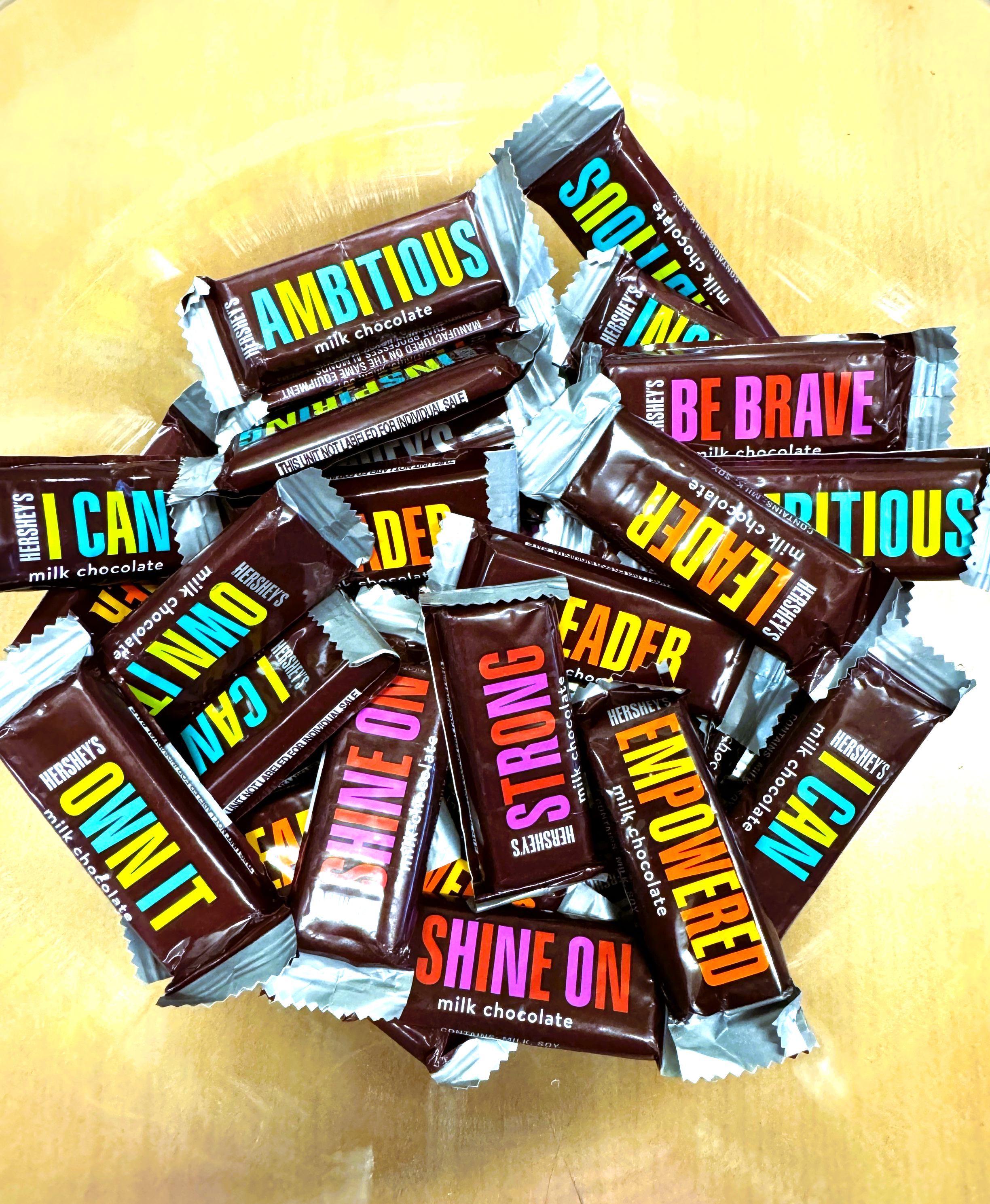 A bowl of inspirational chocolates with words like: be brave, ambitious, leader strong, I can, own it, shine on.