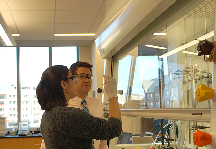 Photo of Prof. Rory Waterman with student in the lab, analyzing chemical reactions.