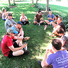 Graduate students sitting in circle on lawn