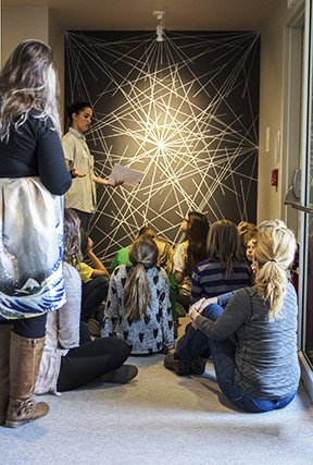 Teacher instructing students in front of art piece