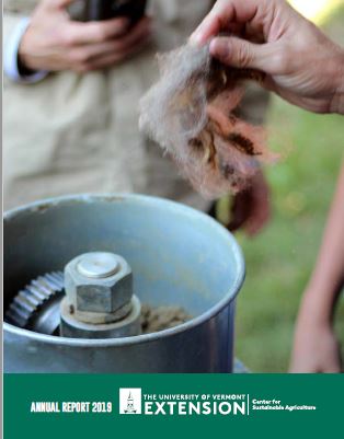 annual report cover: hands are holding raw wool over a blue metal machine with gears