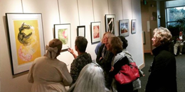 individuals huddled around hanging art in discussion