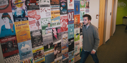 a student walks by a wall of posters in the department of student life