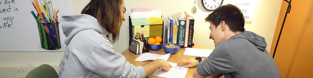 Two students reading a paper together at a round table.