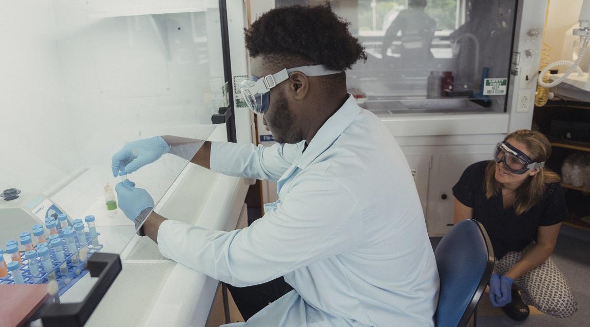Jackson State University student Mouhamadou Kane working with a sample in a lab alongside UVM Graduate Student Bella Bennett