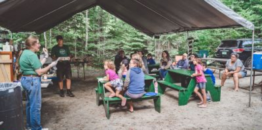 Participants watch an outdoor cooking demonstration
