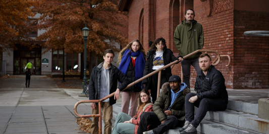student journalists seated on the steps to the Royall Tyler Theatre