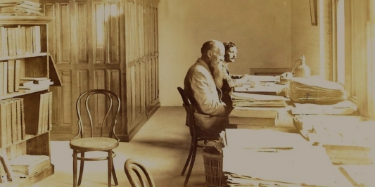 sepia photo of two men seated at their mounting table
