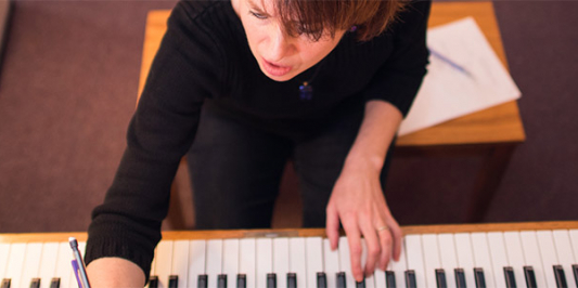 woman compusing music in front of piano