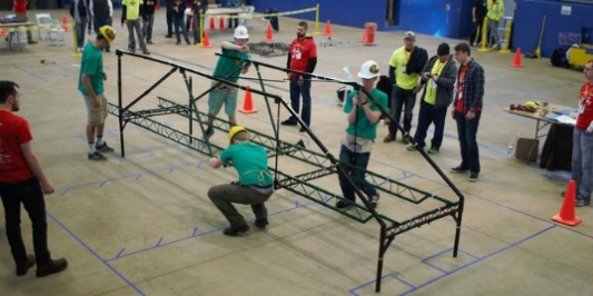 Four students in hard hats assemble a metal structure