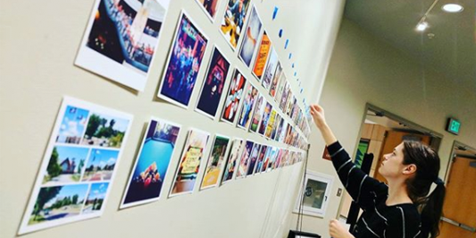 students installing rows of square photos on a wall
