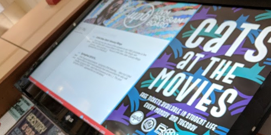 A digital display showing posters and event information on the wall