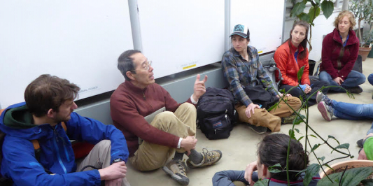a professor talking to students in a greenhouse