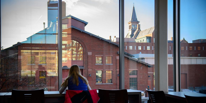 student at table inside looking out over campus