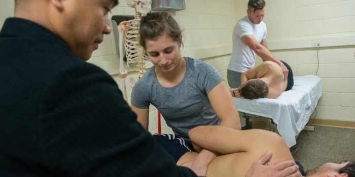 Professor Escorpizo working with students in physical therapy lab.