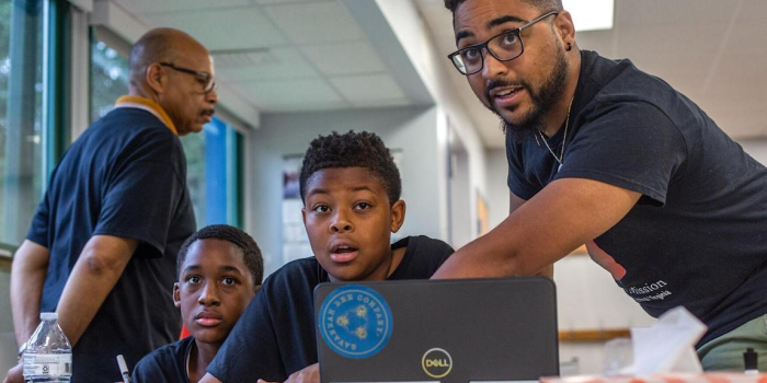 Daniel Farley works with young black males in a school classroom.