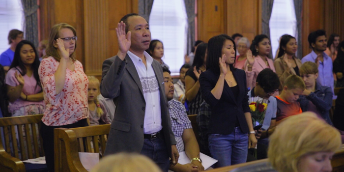 New Americans raising their hand as they take their oath