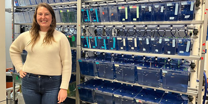 Helaina Stergas standing next to tanks of zebrafish in a lab in Marsh Life Science