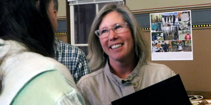 Cherie Morse is shown smiling while talking with a student. She is holding her award casually in her hand.