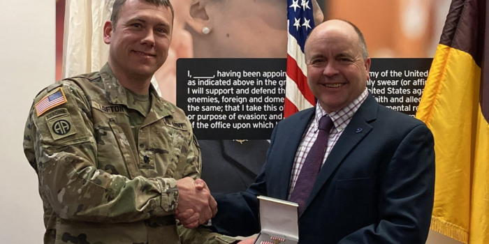 Two people shaking hands, one receiving an award