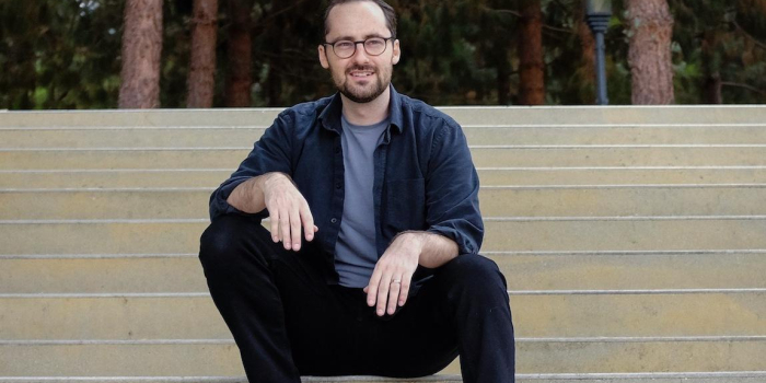 profile photo of CALS alum John Moses sitting on a large outdoor public staircase