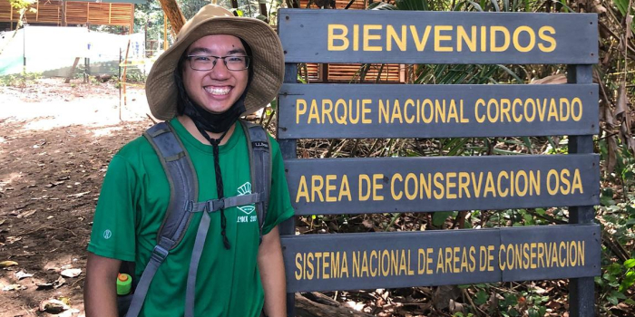 Jonah Stern stands next to wooden sign in Costa Rica.
