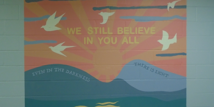 We still believe in you banner on a wall painted bright blue