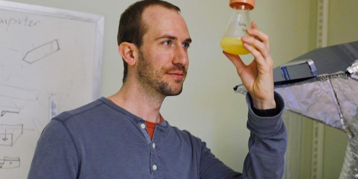 Matthew Grasso holding a beaker in a laboratory.