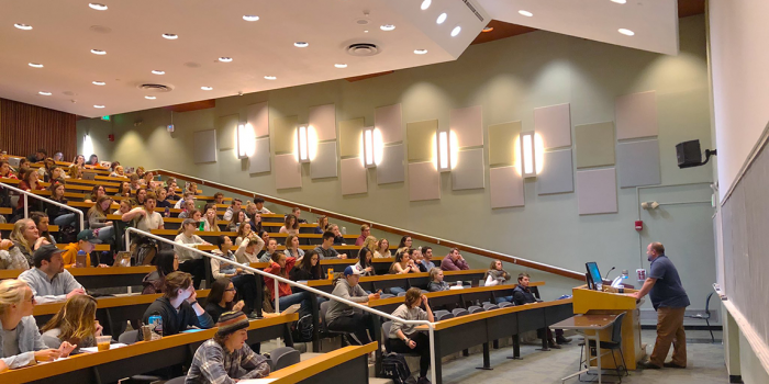 Erik Ruggles at a podium in a large lecture hall