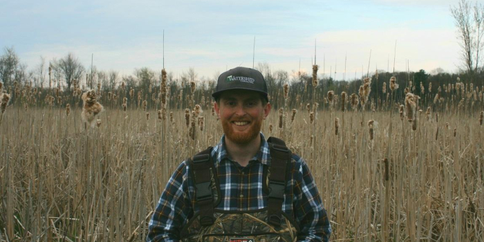 Sam Buswell standing in among reeds in a wetland in Vermont
