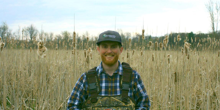 Sam Buswell standing among reeds in a wetland in Vermont