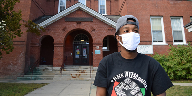 Aden Haji stands in front of Integrated Arts Academy in Burlington's Old North End.